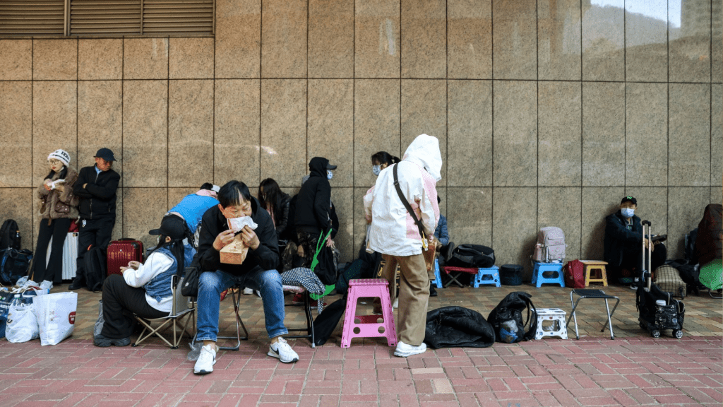 不少人用凳、紙皮、膠袋、雨傘、行李箱等物霸位代為排隊。