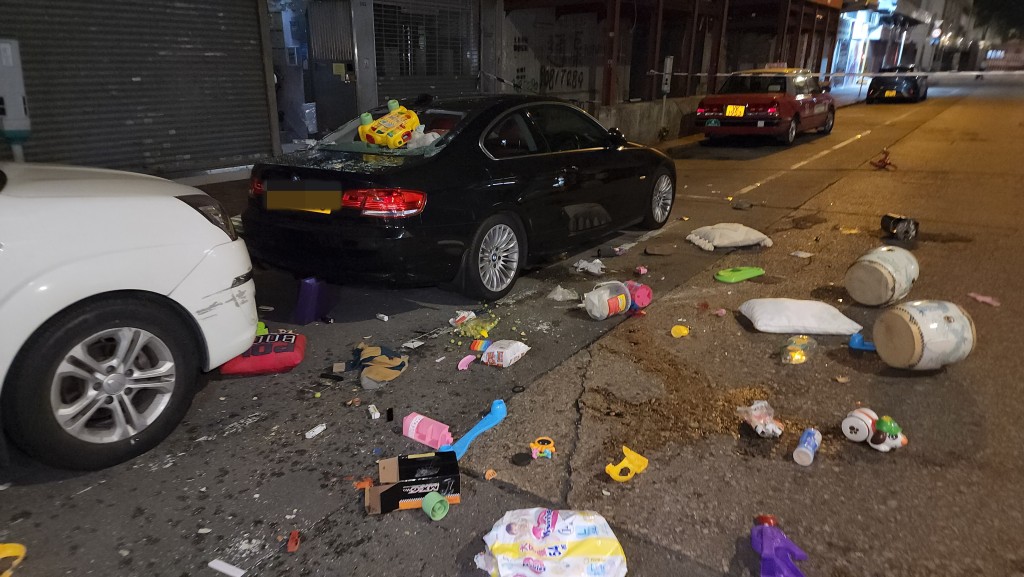 大樓對開馬路布滿玩具及雜物，一輛停泊下方的寶馬損毀。