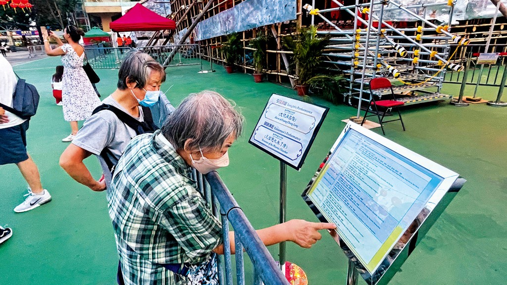 雖然職員表示可以掃描QR Code查看演出資訊，但不少長者不懂使用，唯有在戲棚現場努力地查閱展示牌上的資料。