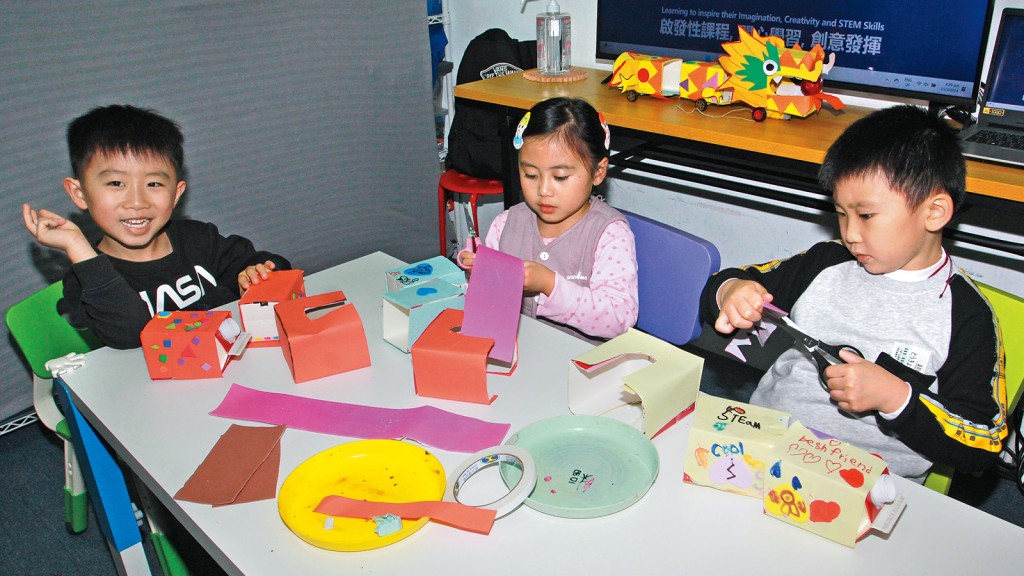 小女孩與導師一起剪裁紙條用來裝飾紙盒，發揮協作精神。