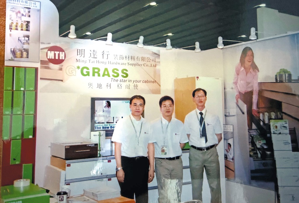 香港回歸是鄺錦明一生最大轉捩點，他接手裝飾五金材料批發行不久，便在會展展出公司代理的奧地利製櫥櫃門鉸及路軌產品。