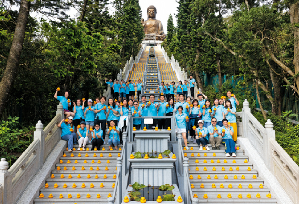 360 義工隊合力將近五千隻橡皮鴨，排列在全球最高的戶外青銅坐佛天壇大佛的石階上。