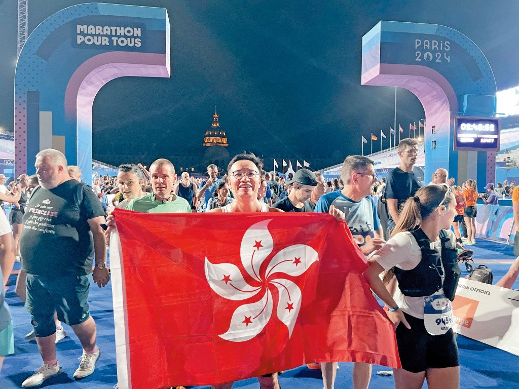 二〇二四巴黎奧運歷史性舉辦「大眾馬拉松」,蕭粵中是香港廿多名獲抽中參與的幸運兒之一,他刻意拿着區旗衝線。 二〇二四巴黎奧運歷史性舉辦「大眾馬拉松」,蕭粵中是香港廿多名獲抽中參與的幸運兒之一,他刻意拿着區旗衝線。