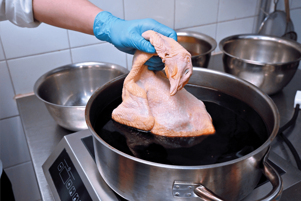 1. 原隻鮮雞洗淨及瀝乾水，雞身內外以鹽、胡椒粉及玫瑰露抹勻，放入煮滾的浸雞醬汁中浸熟。