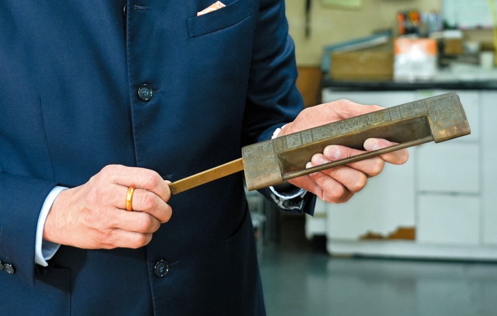 鄺錦明愛收集古鎖，手中是其收藏之一的銅古鎖。