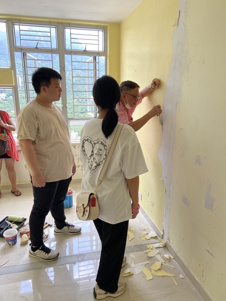 退休後的開叔選擇為街坊維修家居，圖中教授學員如何剷走批盪。