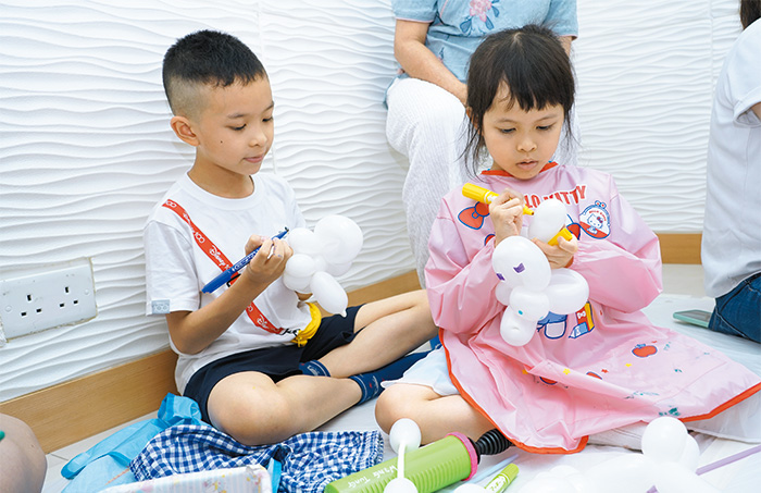 兩兄妹在氣球上畫花紋，自由發揮藝術天份。